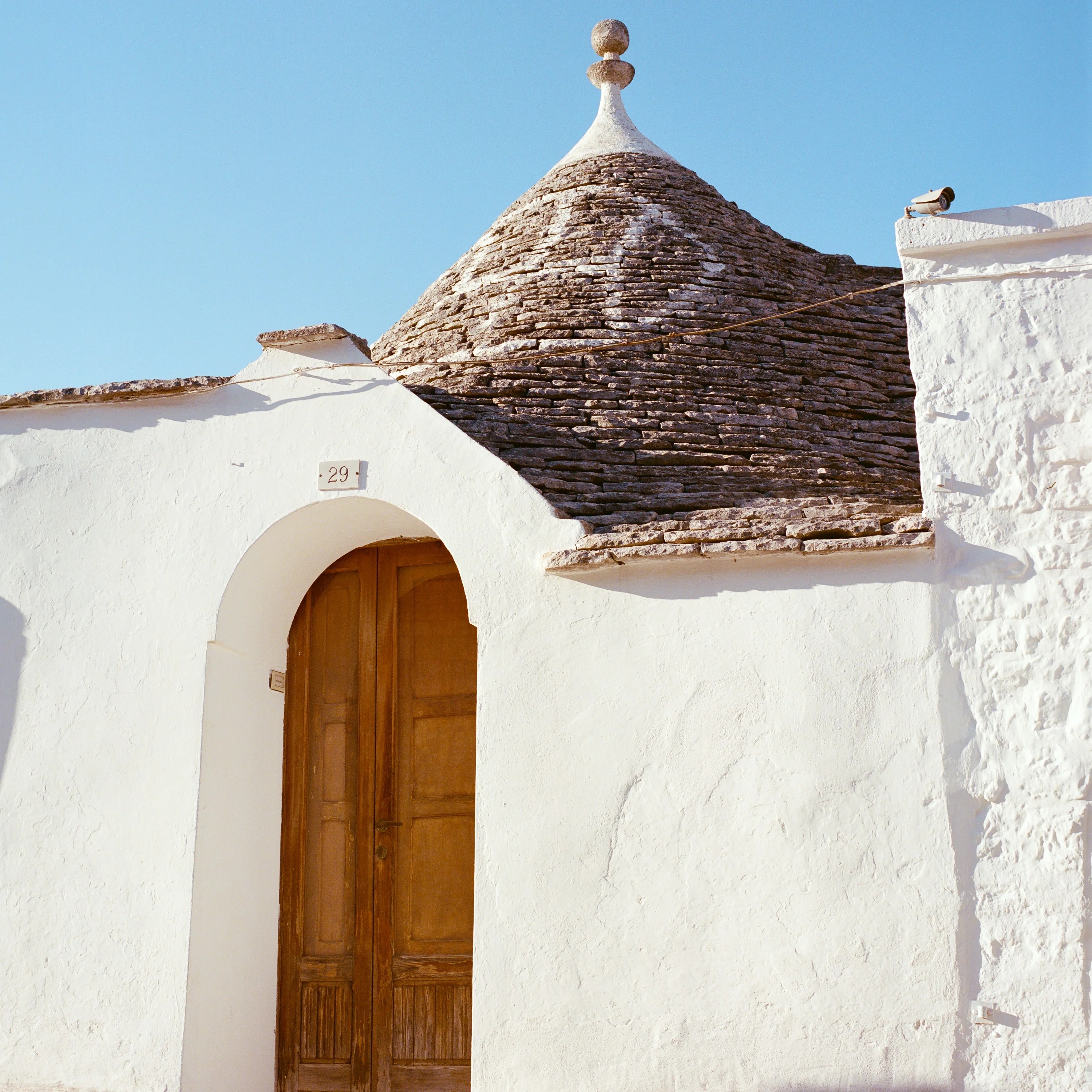 A wooden door in a whitewashed trullo with a stone cone roof
