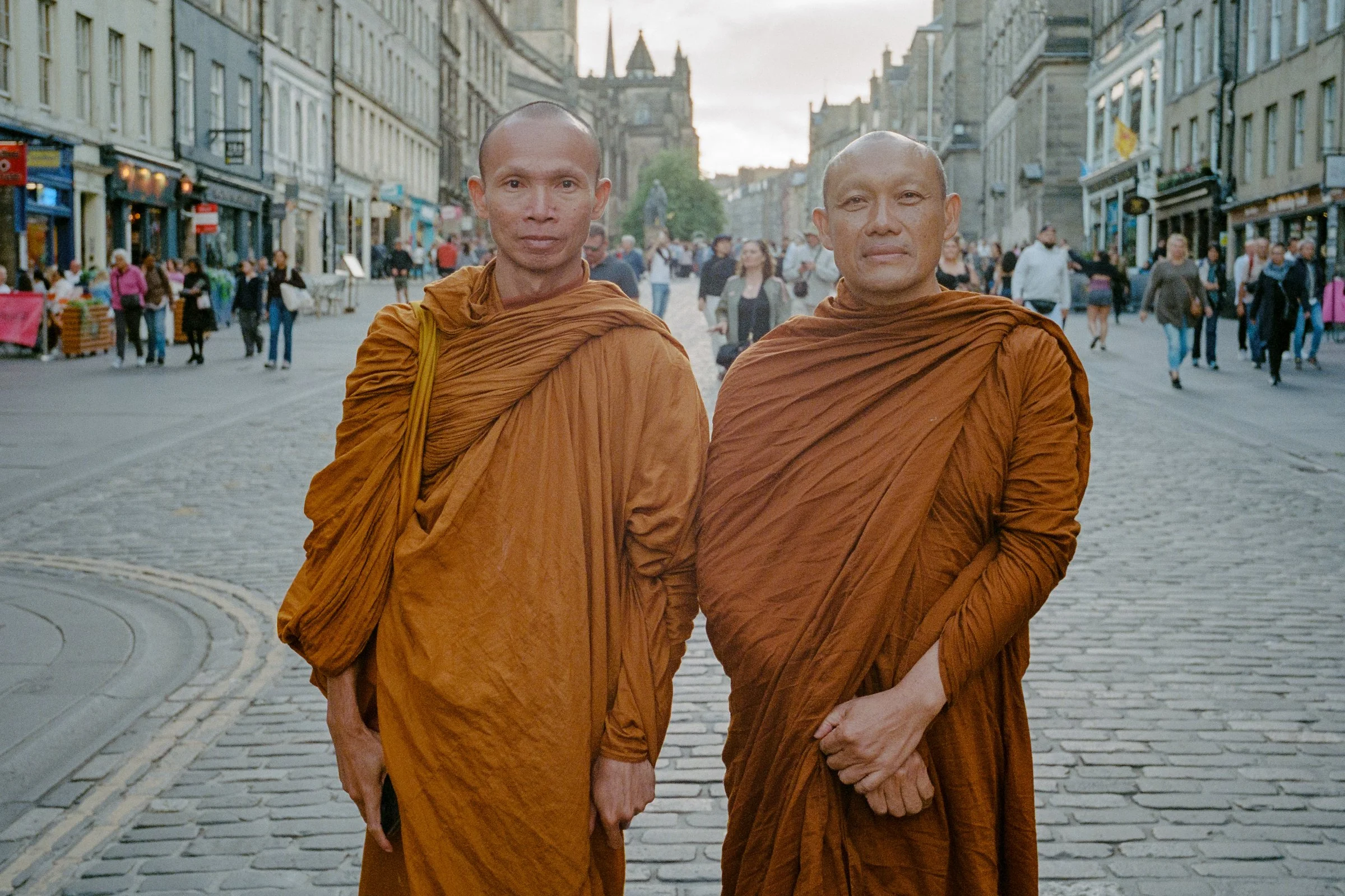 Two Buddhist monks in saffron robes standing on the cobbles of the Royal Mile