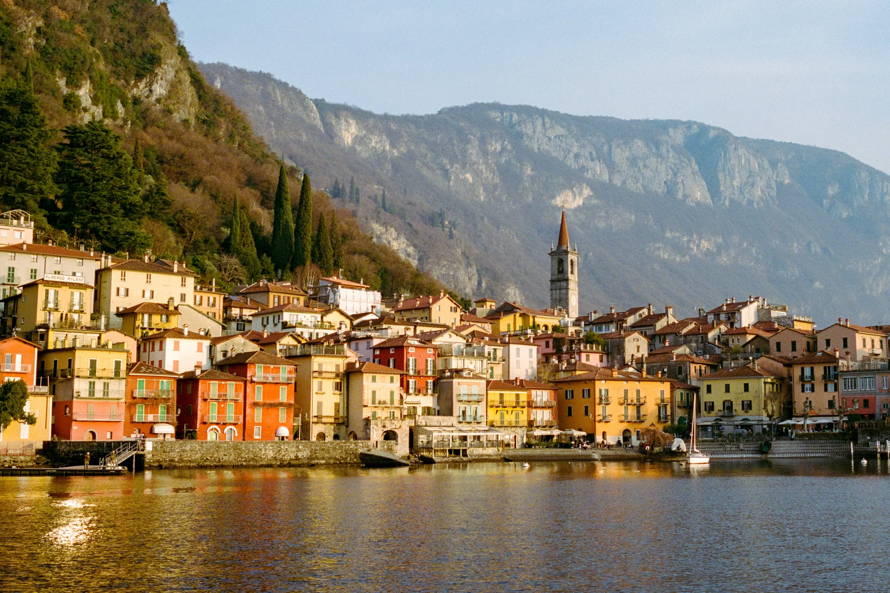 Colourful houses along the shore of Lake Como below steep green mountains