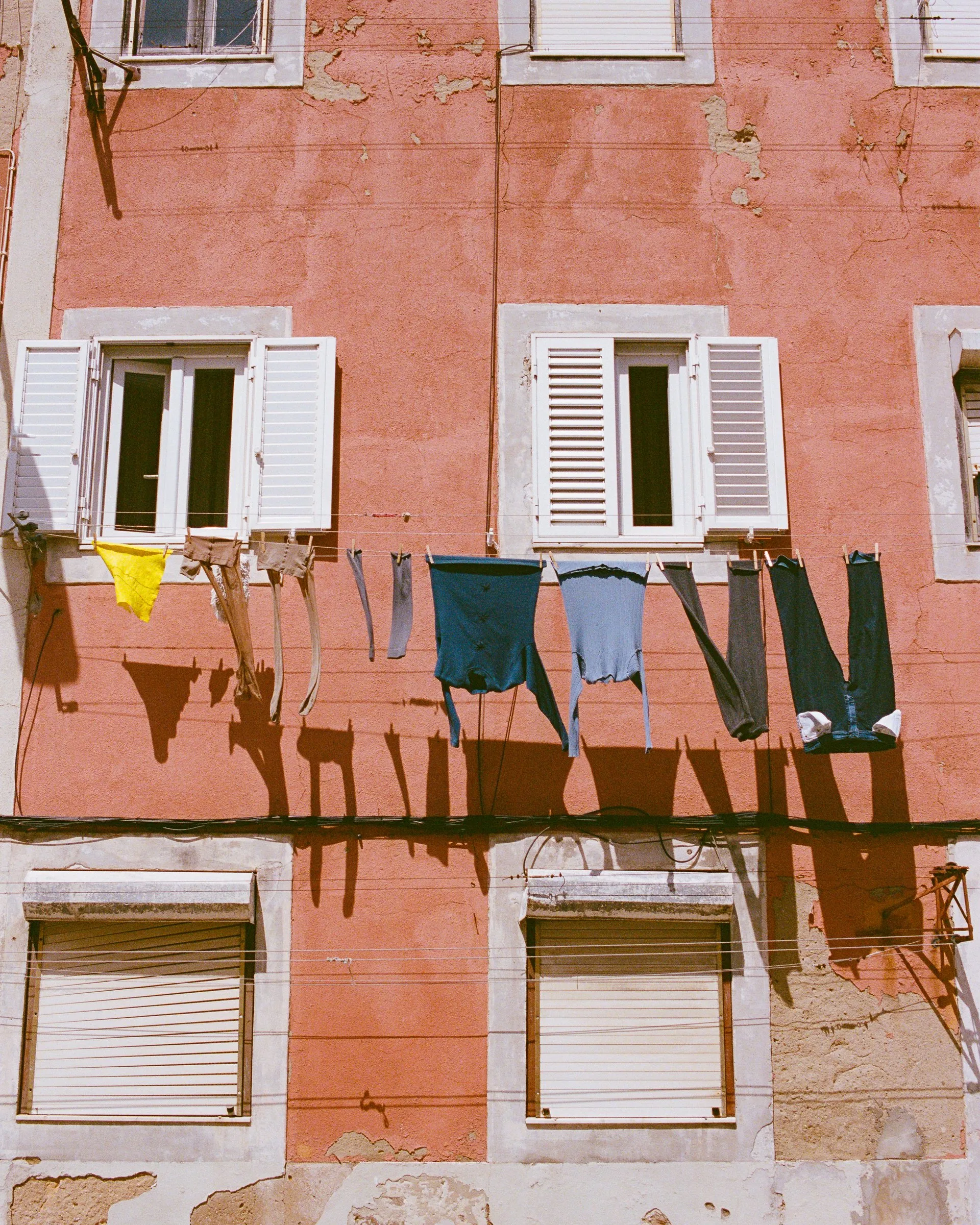 Clothes drying on a line across a pink wall