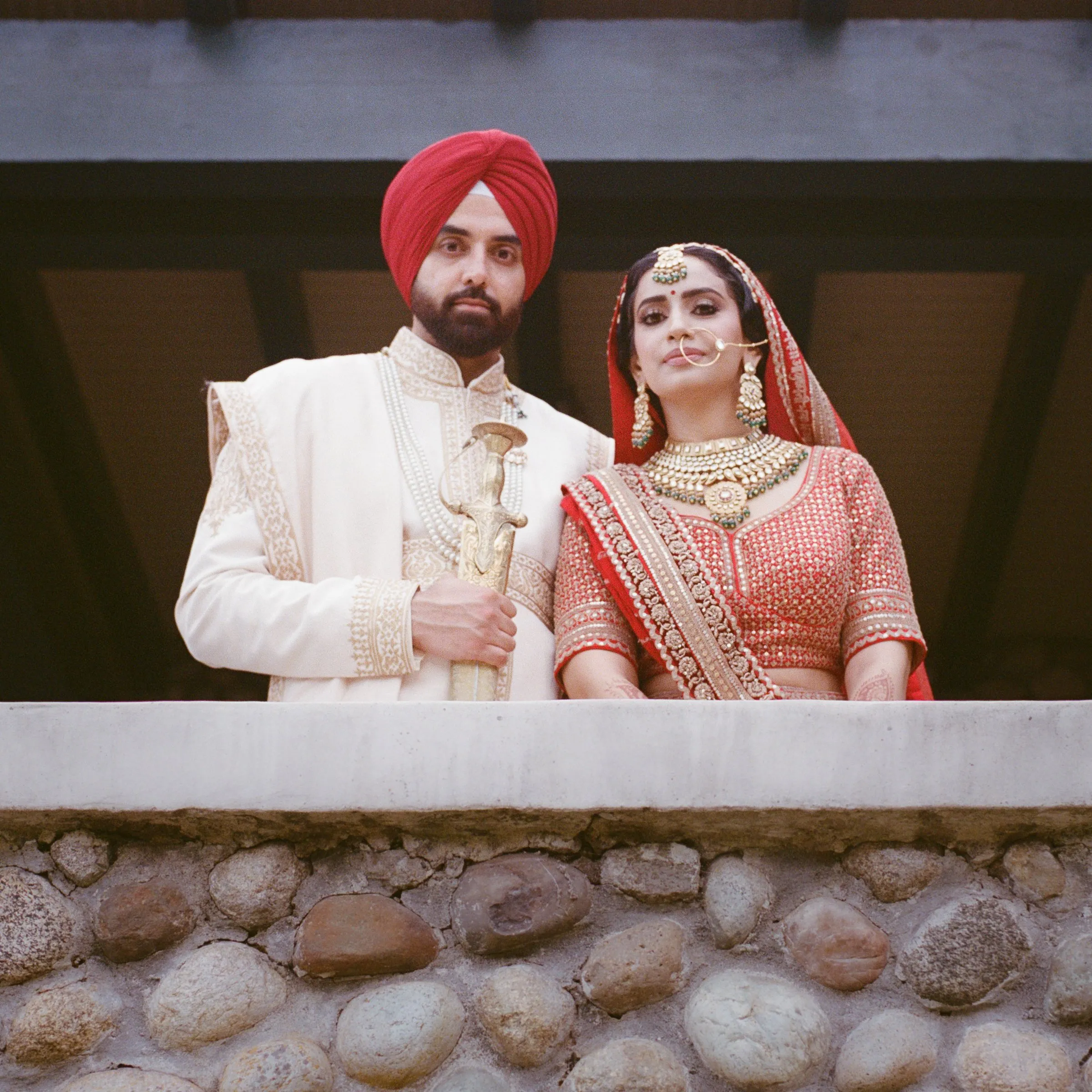 A bride and groom smiling on a stone balcony