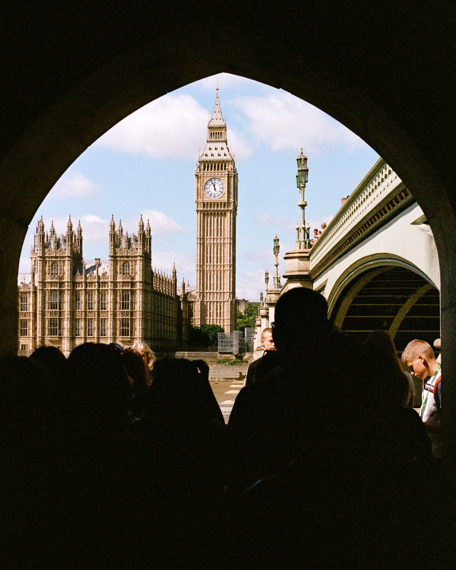 Big Ben framed by a dark pointed arch with silhouettes of people