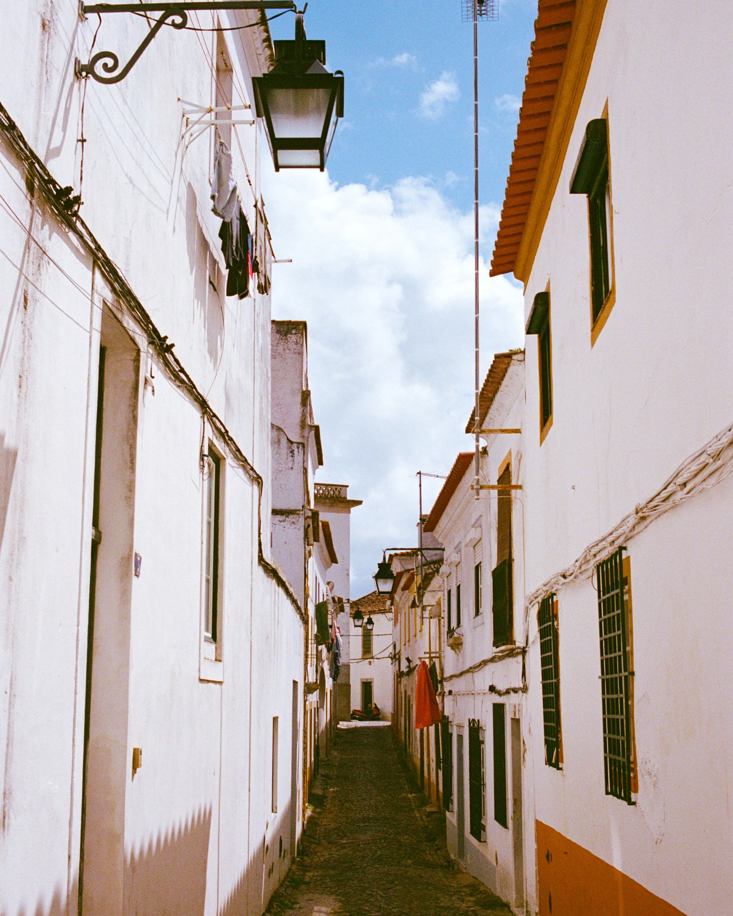 A narrow white alley under blue sky