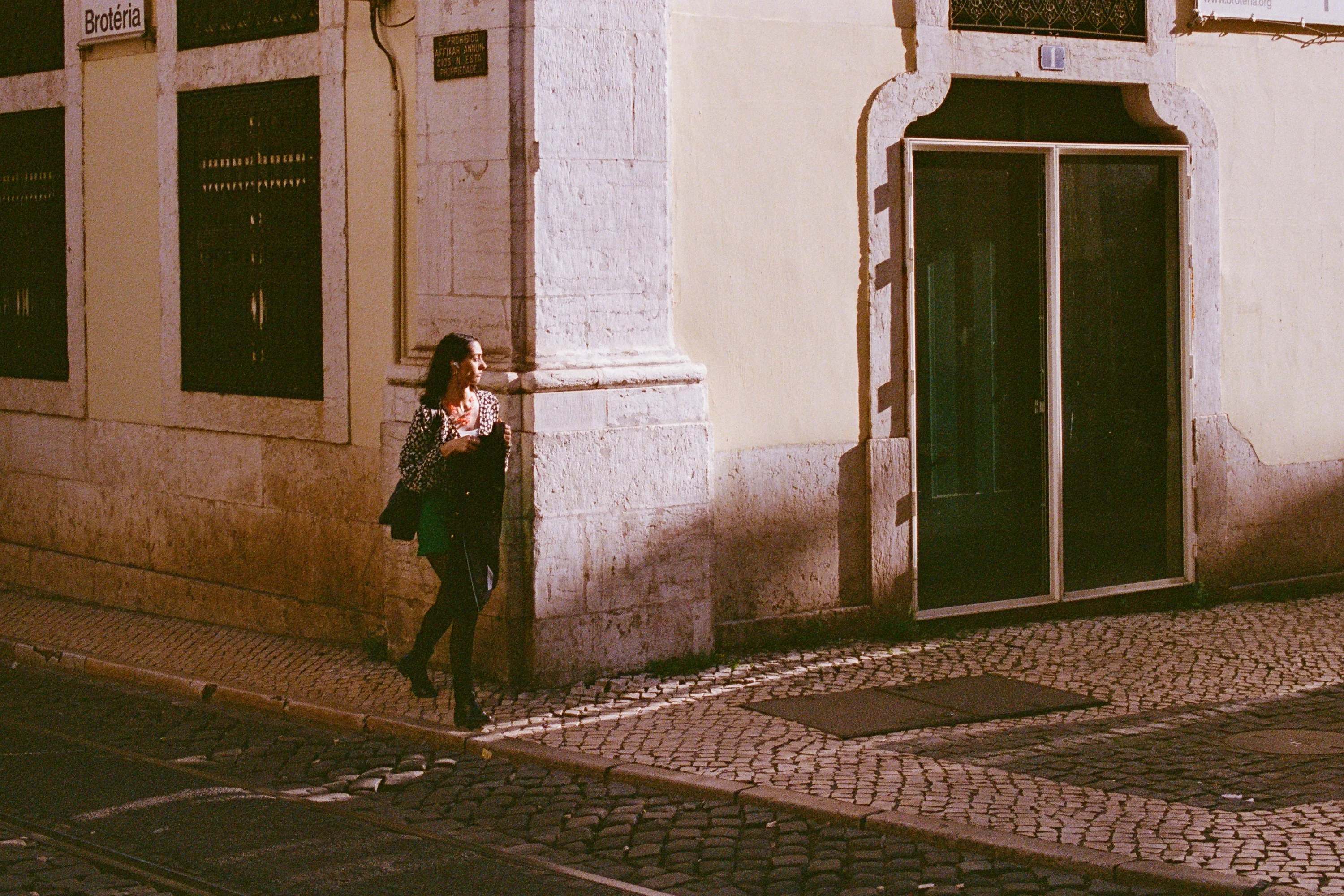 A woman walking past a green door on a corner
